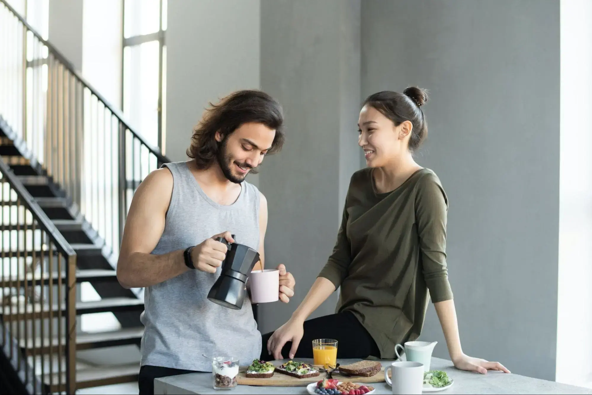 Happy couple in their kitchen sharing coffee in the morning.