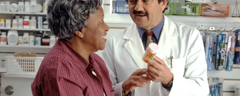 An elderly woman receiving medication from her pharmacist.