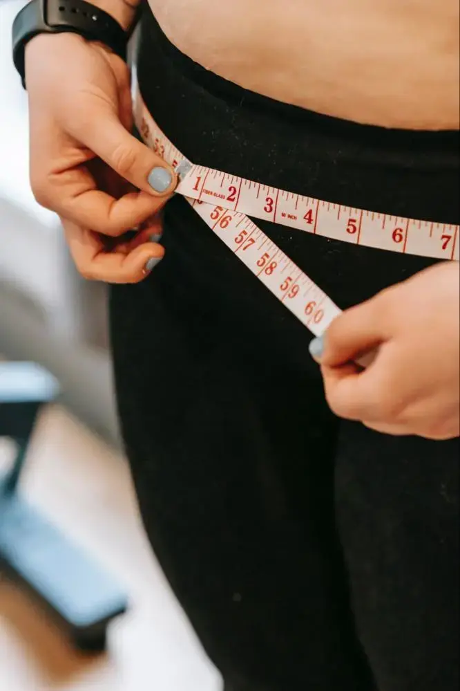 A person measuring their waist to see if they qualify for weight loss surgery.
