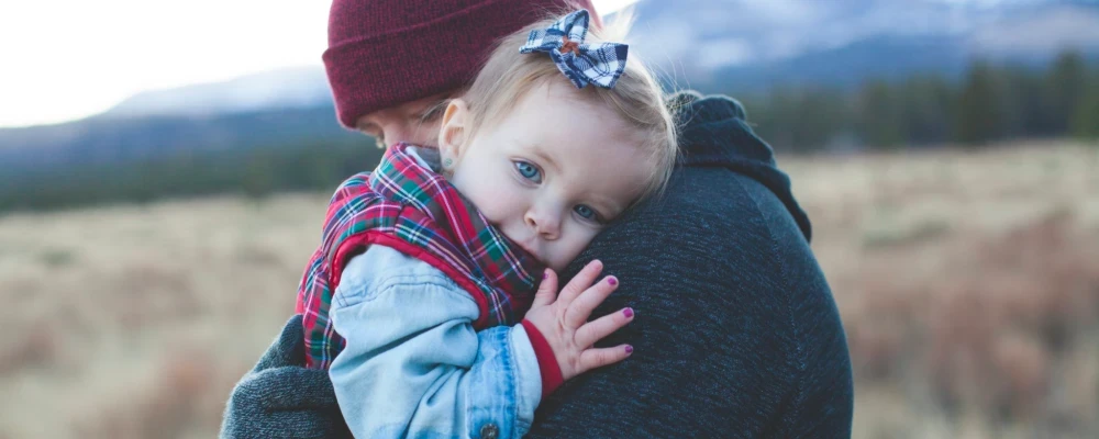 Mom with beanie on holding baby in the outdoors